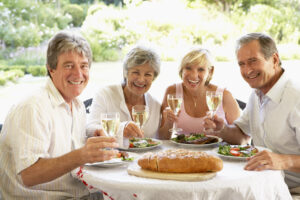 Four senior friends eating lunch and socializing while siting at an outdoor patio