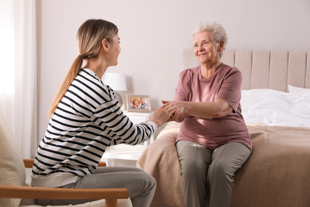 Senior sitting on her bed at her new Alzheimer's and dementia care Elkhorn apartment with daughter