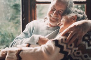 A senior couple smiles as they embrace and laugh