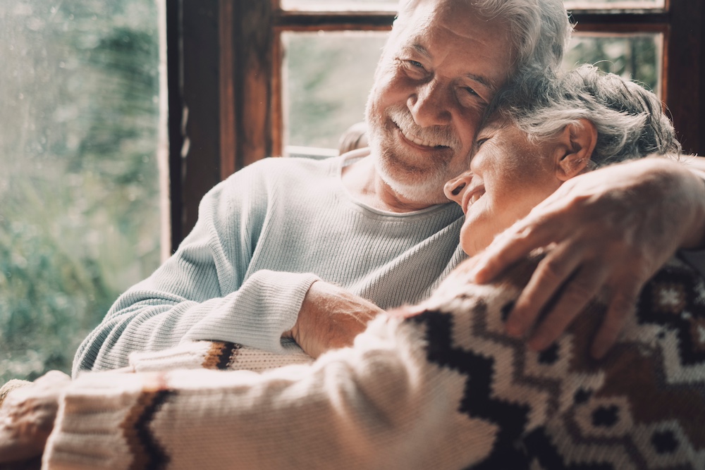 A senior couple smiles as they embrace and laugh