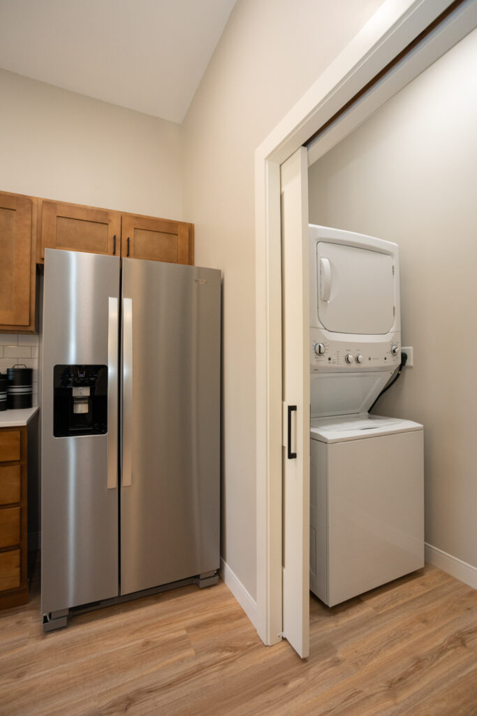 A full-sized fridge and a stacked washer/dryer.